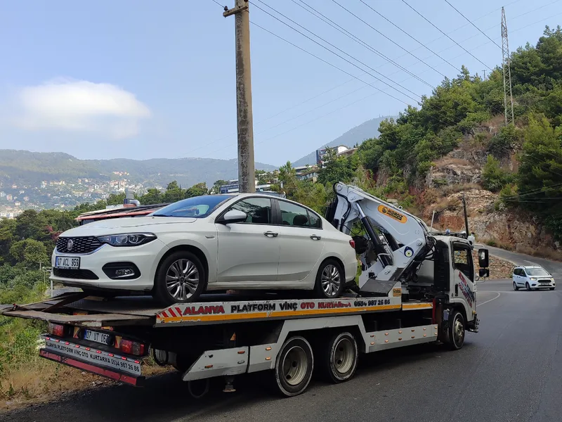 Platformlu kurtarıcı üzerinde taşınan beyaz otomobil